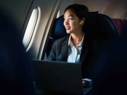 Successful Asian business woman working in airplane cabin during flight small