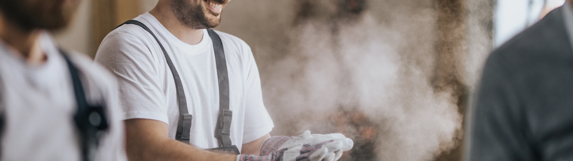 Happy construction worker with dusty gloves