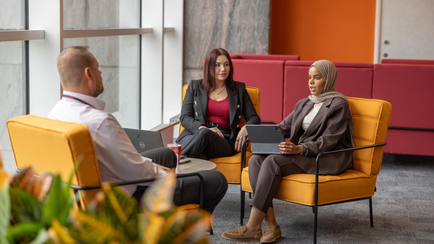 Two women and man on orange seats meeting image